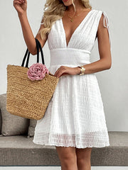 White textured smocked deep V-neck a-line dress with tie shoulder straps, cinched waist, and above-knee length.