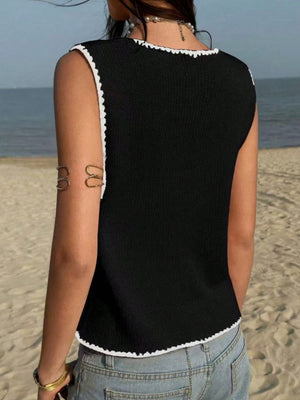 Black knit sweater vest with white trim and scalloped edges.