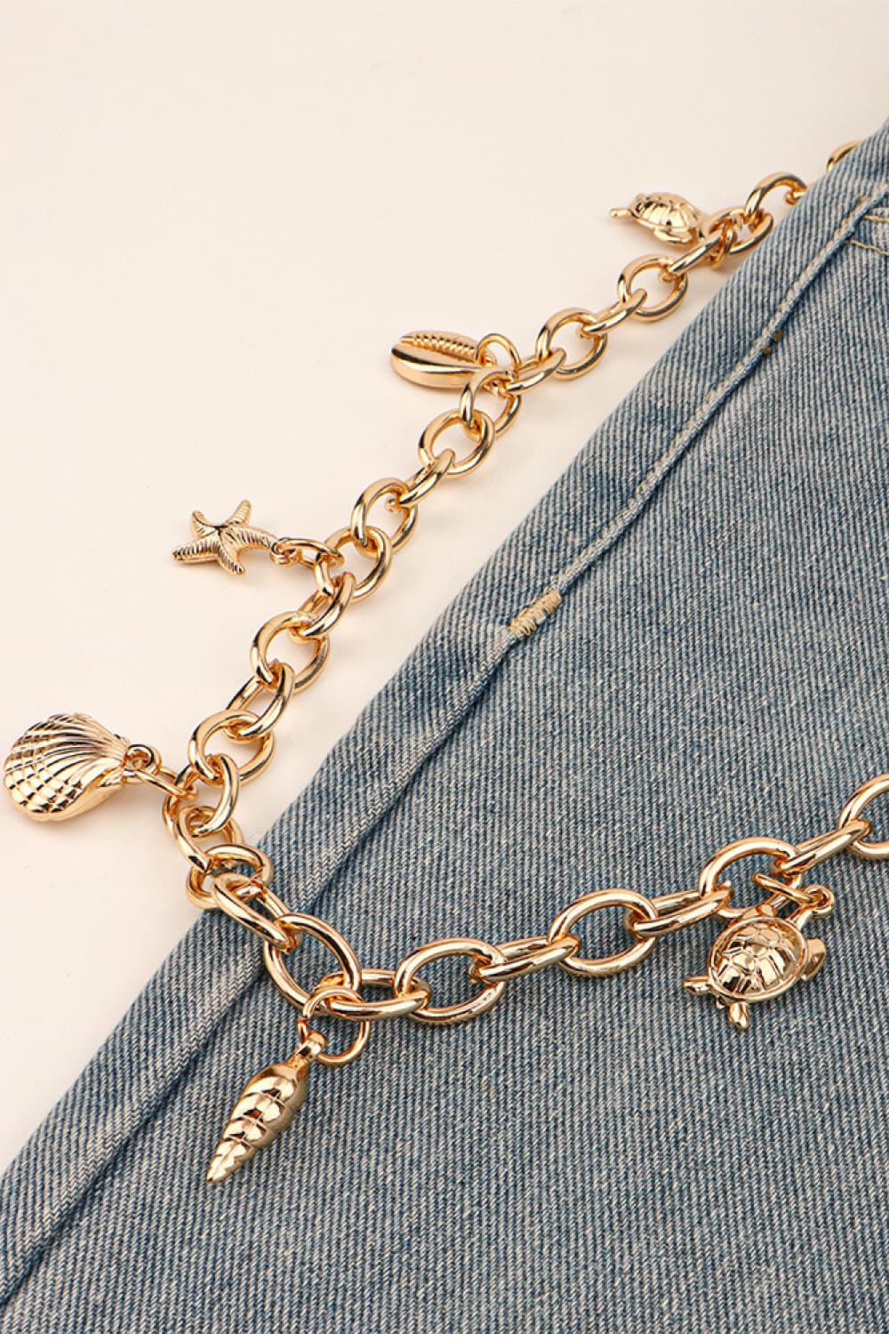 Gold chain belt with seashell, starfish, turtle, and cone charms.