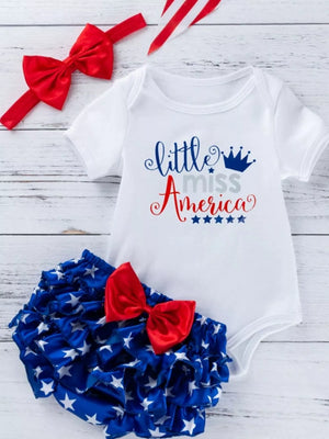 Patriotic baby outfit with white bodysuit and ruffled star bloomer, red bow headband.