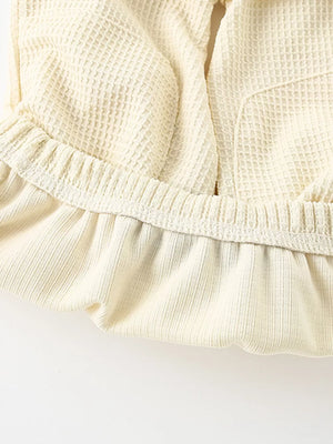 Beige waffle knit toddler tee and shorts set detail with ruffled hem and elastic waistband.