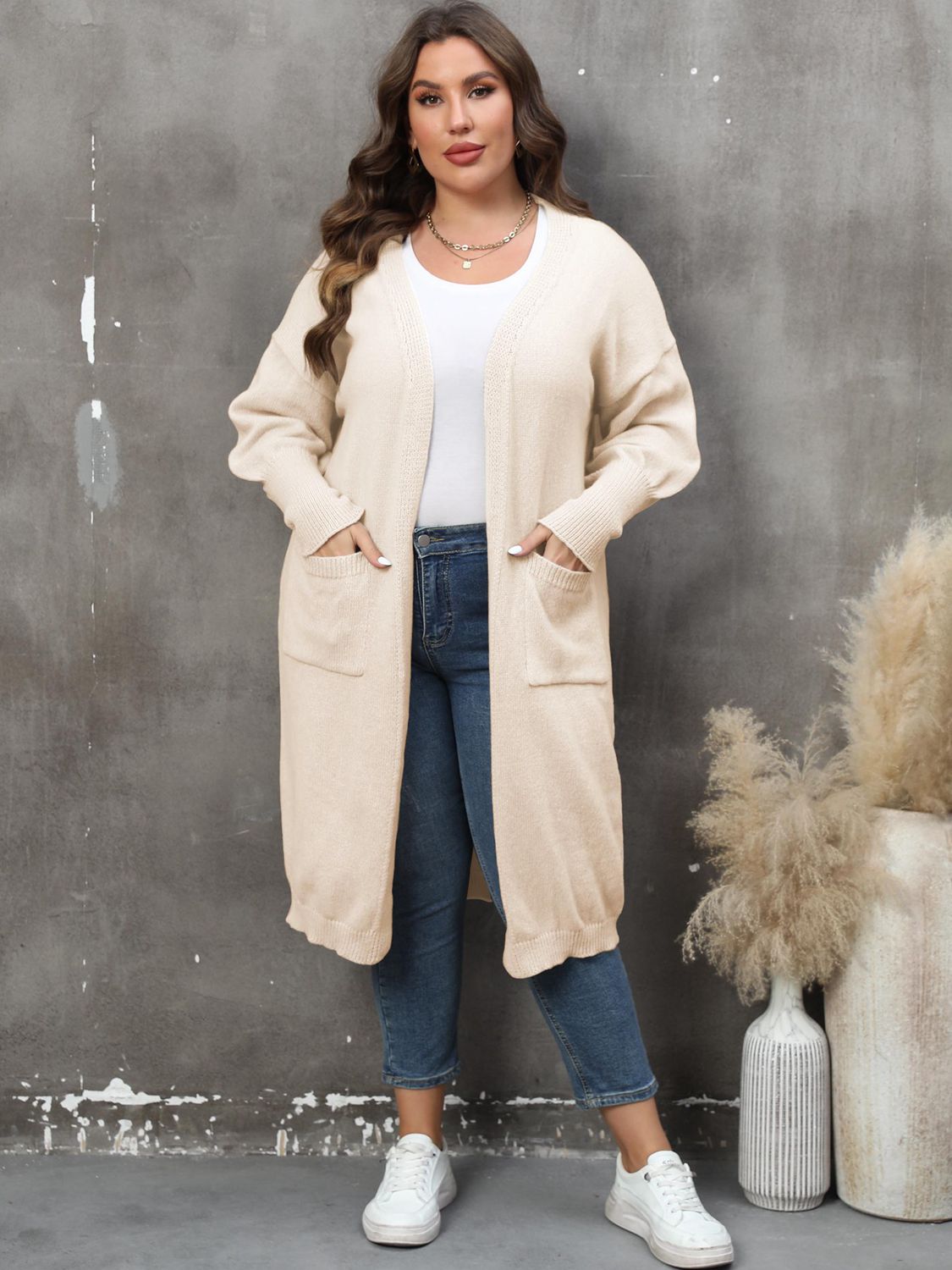 Cream oversized knit duster cardigan with patch pockets and open front.