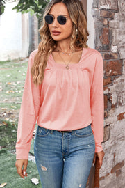 Pleated square neck long sleeve top in watermelon pink, styled with jeans.