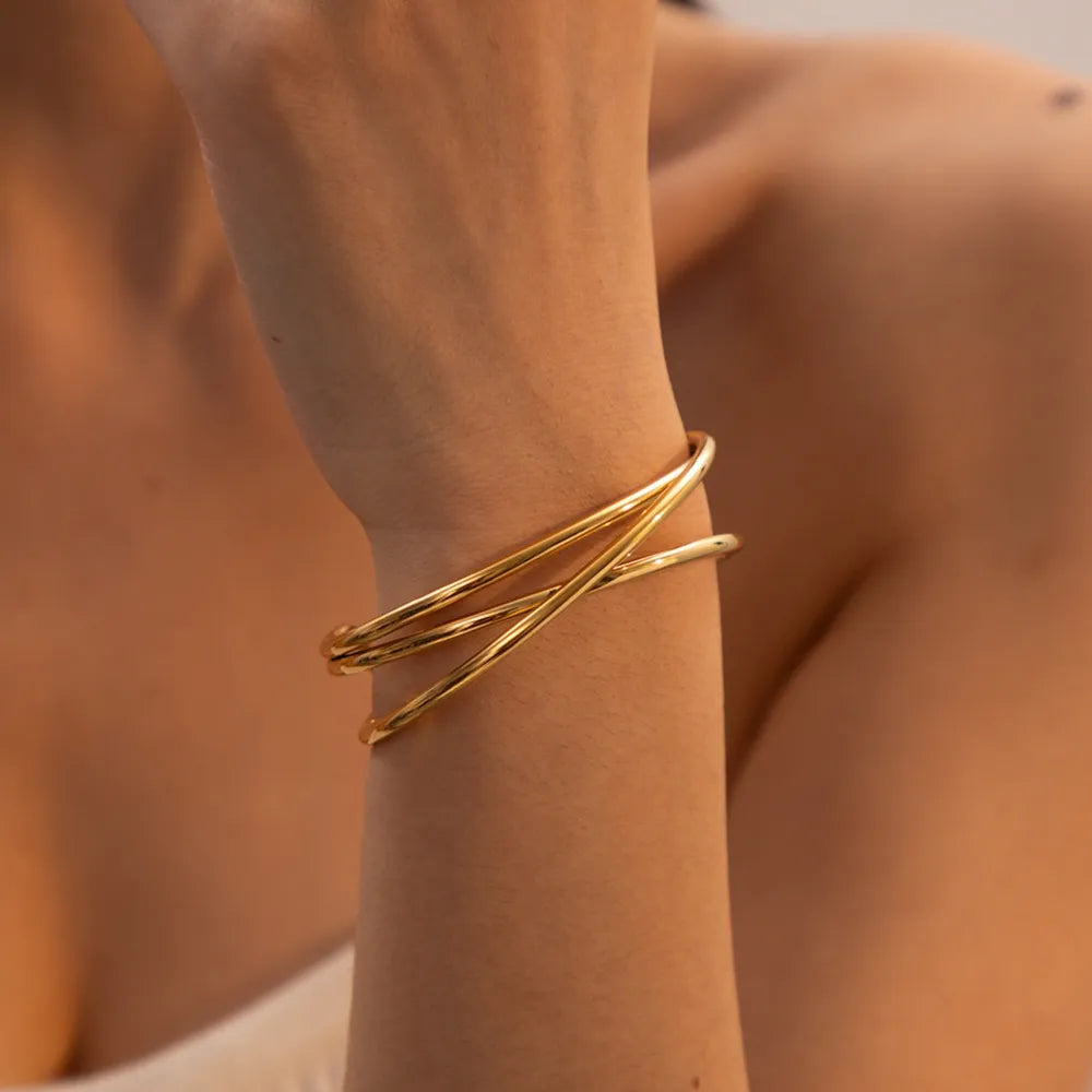 Gold-tone open cuff bracelet with intertwined thin bands.