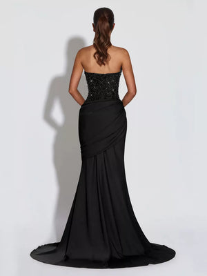 Black sequin corset maxi gown with draped skirt and lace-up back detail.