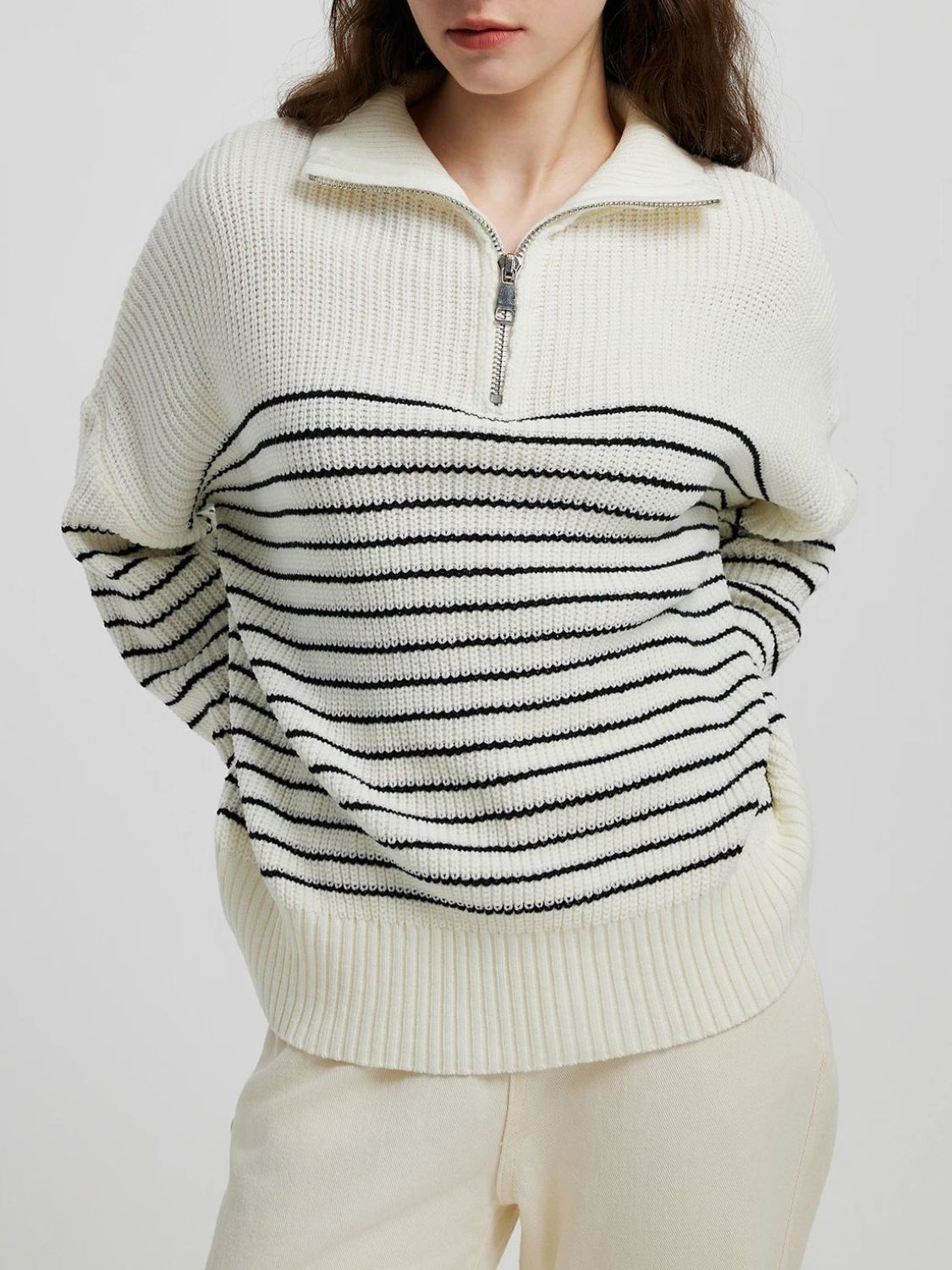 Cream ribbed knit sweater with black stripes and a half-zip neckline.