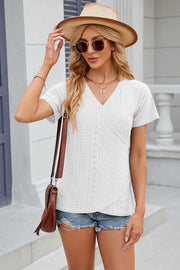 White eyelet wrap v-neck short sleeve blouse with a crossover hem detail.