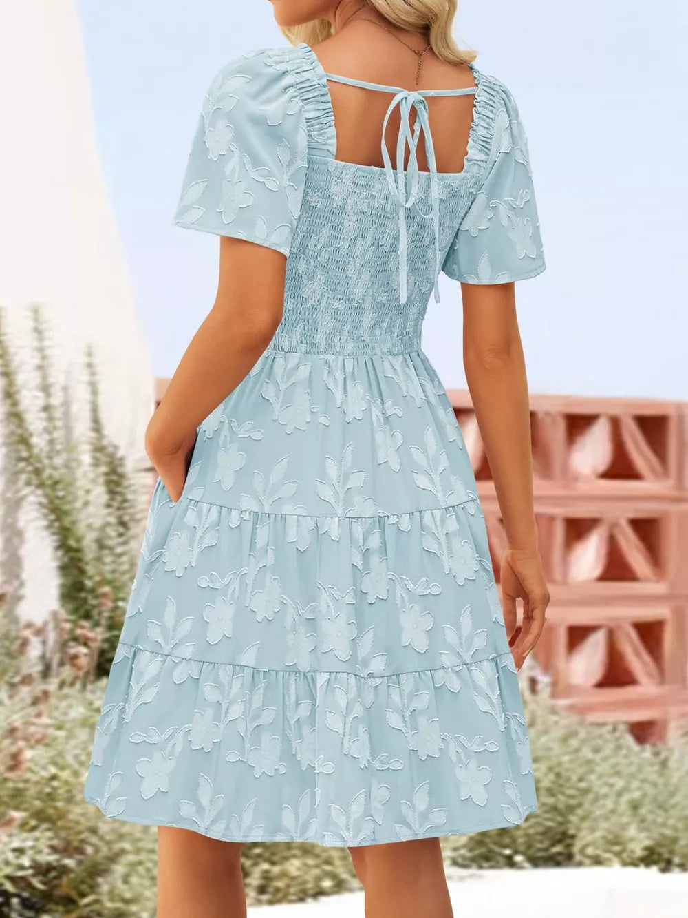 Light blue smocked mini dress with tiered skirt and floral embroidery.