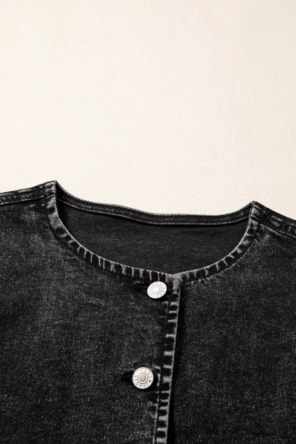 Black denim vest with button front and round neckline.