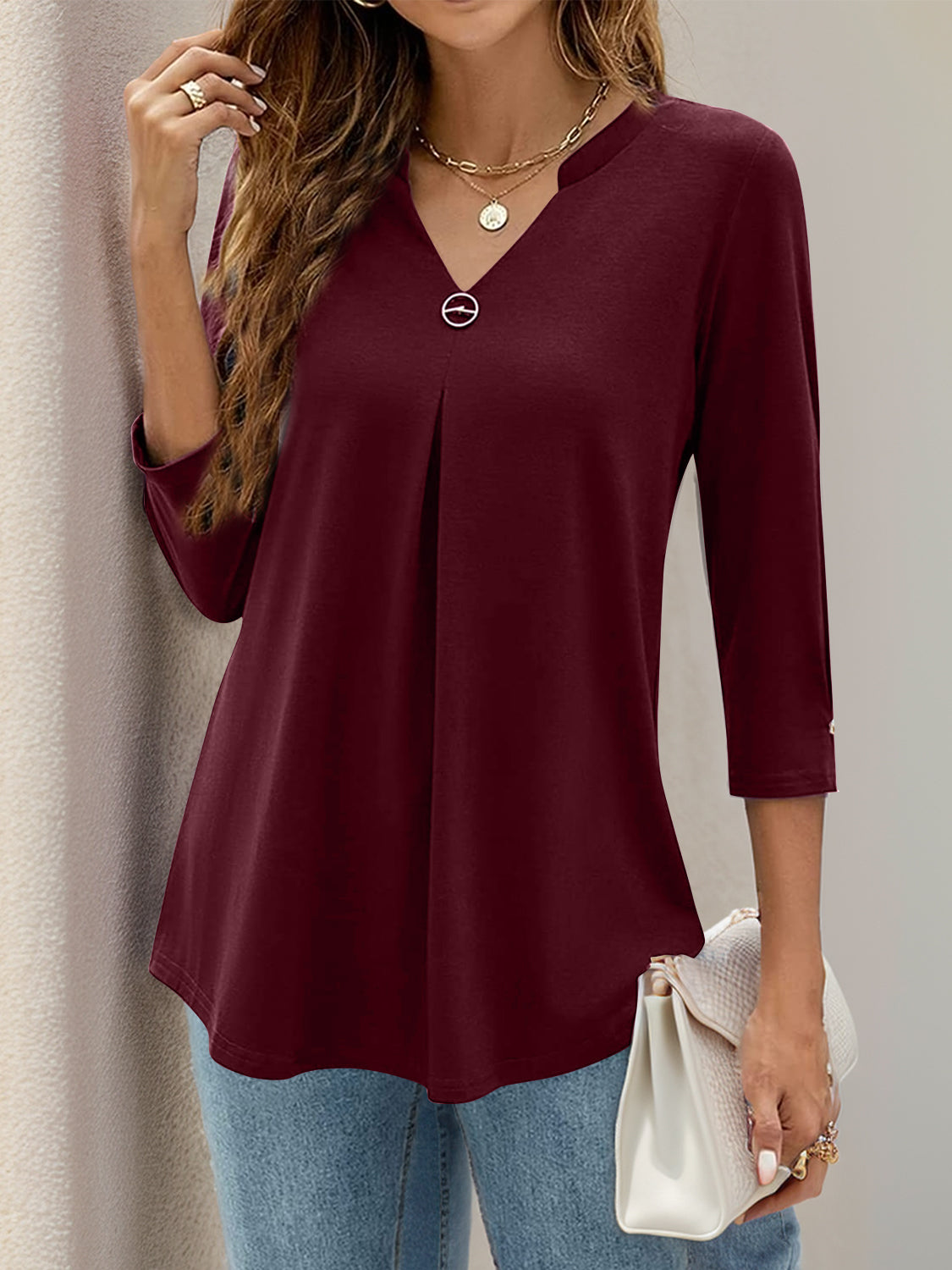 Burgundy V-neck three-quarter sleeve top with front pleats and a decorative button detail.