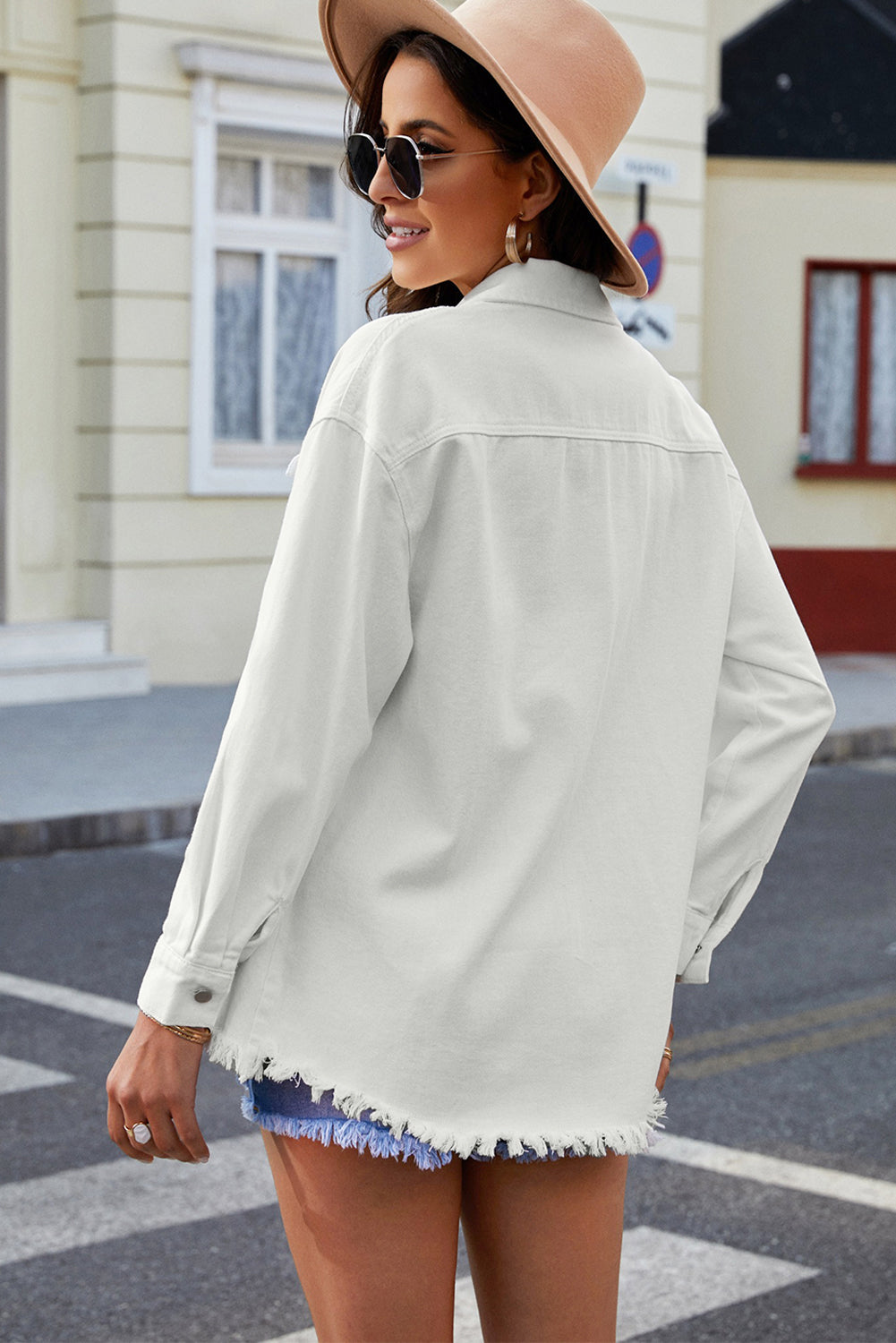 White oversized denim shirt jacket with frayed hem and button cuffs.