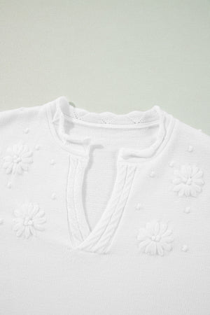 White embroidered floral knit sweater with notch neck and textured details.