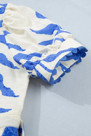 Maxi dress with botanical print, blue accents, and scalloped sleeve trim.