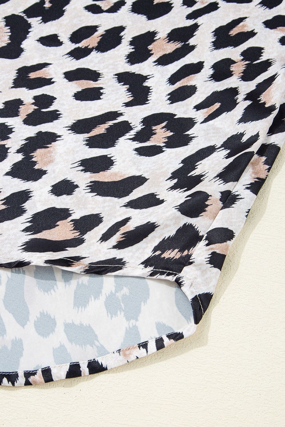 Leopard print oversized button-down blouse with a curved hem detail.
