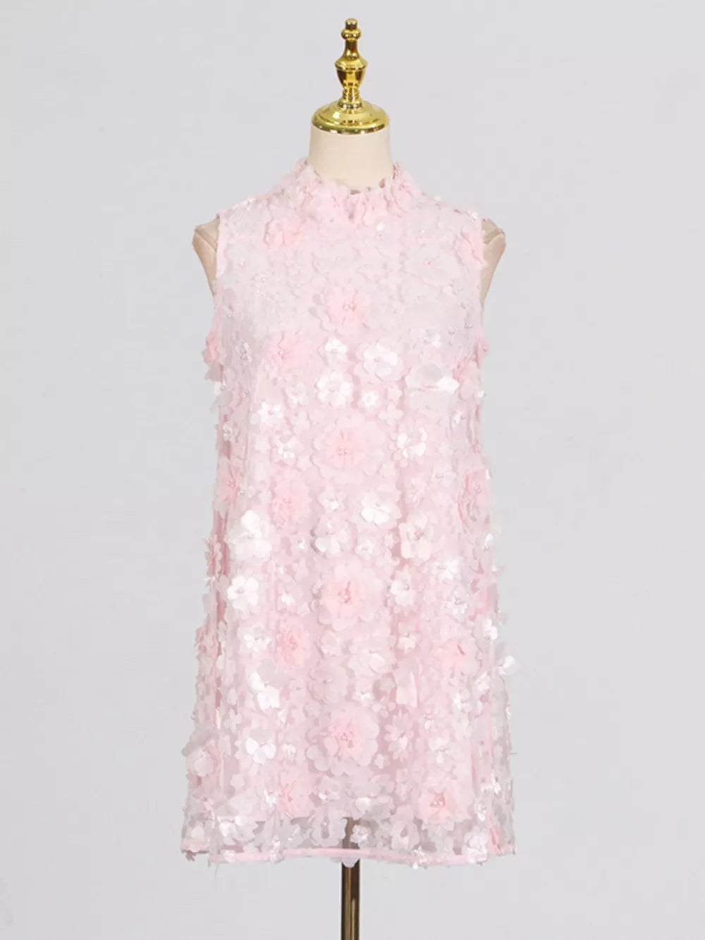 Pink ruffled floral applique mini dress with a mock neck and sleeveless design.