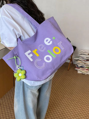 Lavender canvas shoulder bag with embroidered "Free Color" text and flower charm