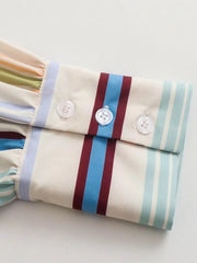 Prismatic stripe band collar blouse with buttoned cuffs and ruffled sleeve detail.