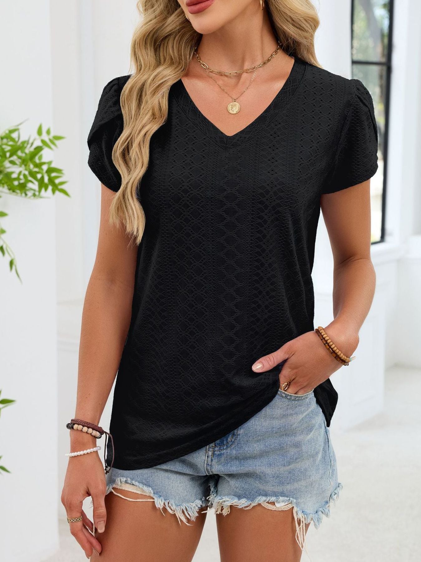 Black eyelet petal sleeve v-neck tee with textured pattern.