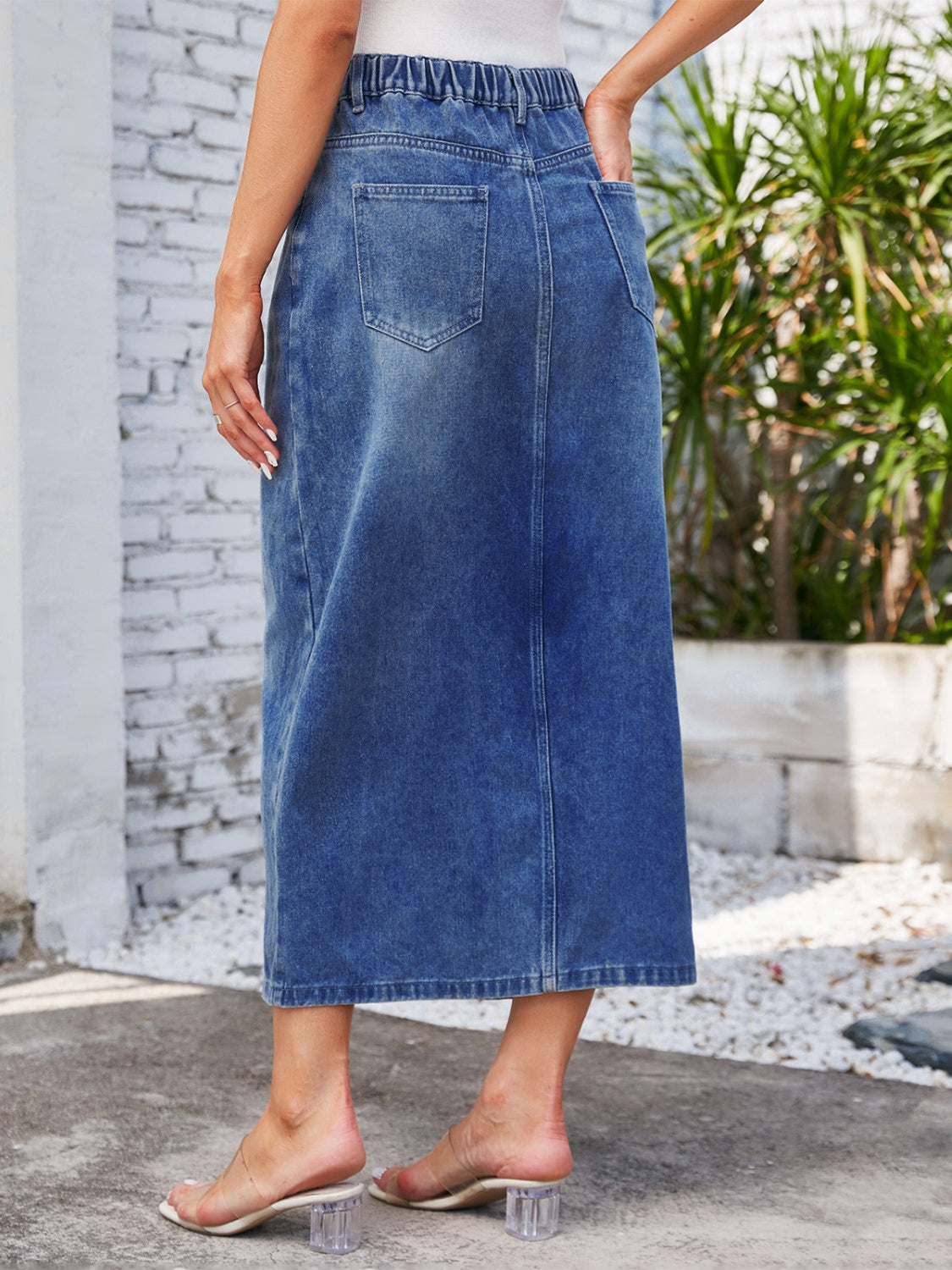 Light blue denim midi skirt with elastic waist and slit detail, featuring back pockets.
