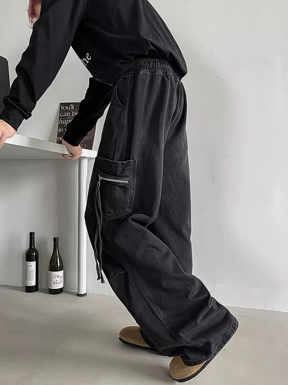 Relaxed fit black denim cargo jeans with drawstring waist and zippered pocket detail.