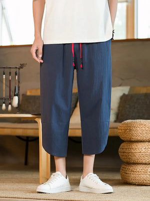 Navy blue cropped sweatpants with red drawstring and cuffed hem.