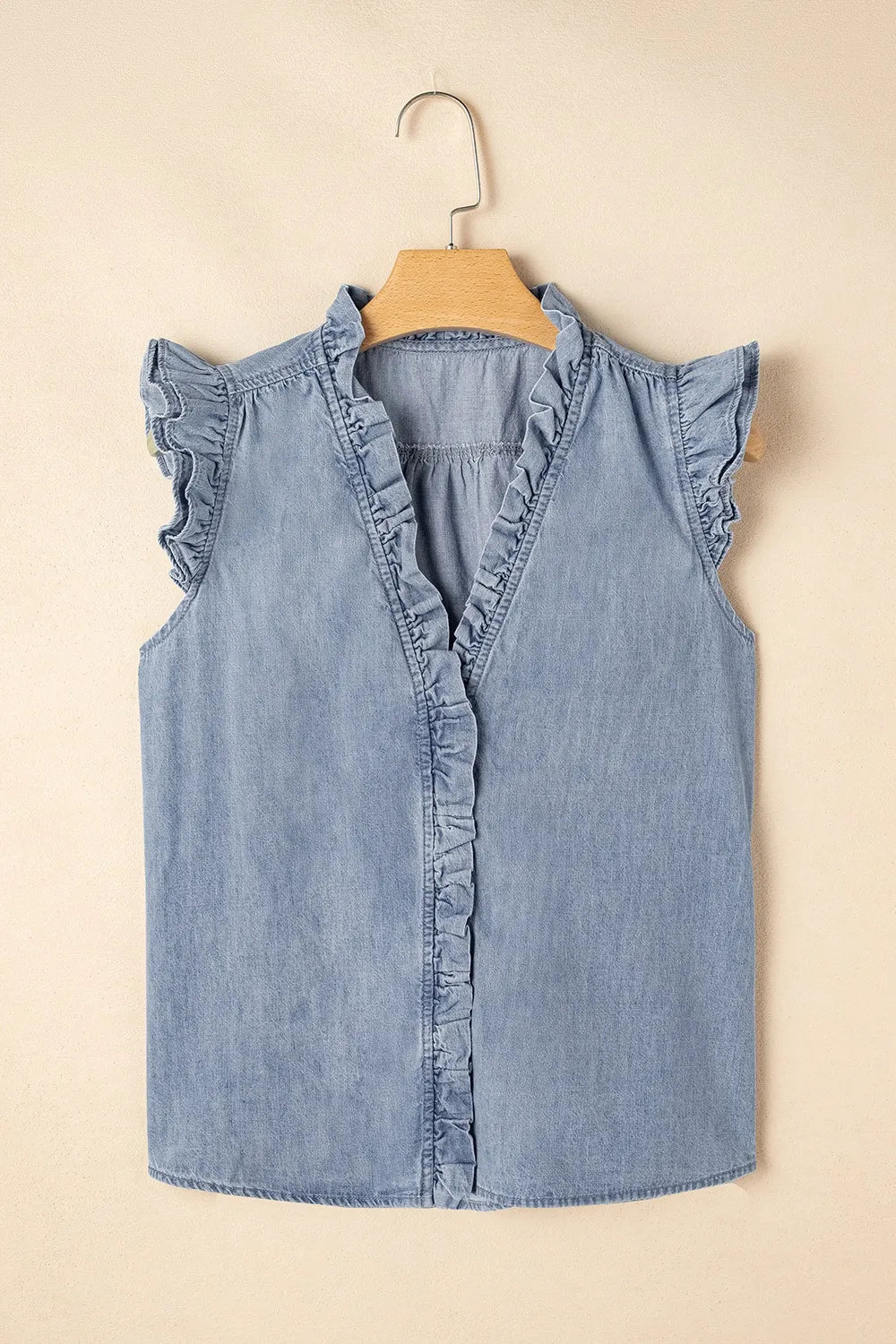 Chambray ruffle trim sleeveless blouse in medium blue cotton with V-neck and button front.
