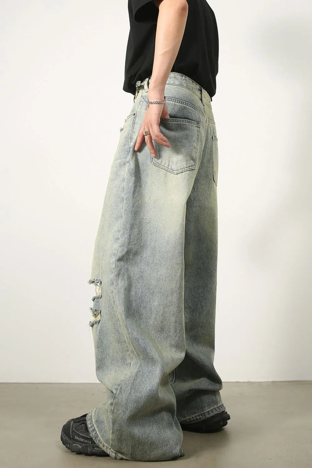 Oversized light wash denim palazzo trousers with distressed details and wide legs.