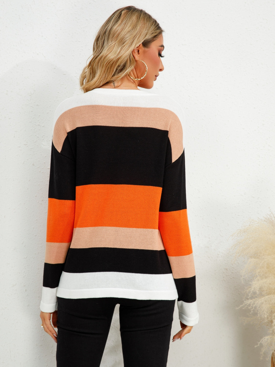 Colorblock crewneck knit sweater with orange, black, tan, and white stripes.