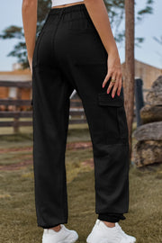 Black cargo pants with multiple pockets and elastic cuffs, styled with white sneakers.