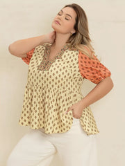 Vibrant geometric peplum shirt with coral sleeves and V-neck, perfect for curvy women.