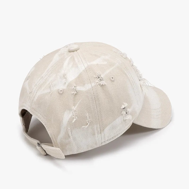 Shredded canvas baseball cap in ivory with distressed details and a tie-dye effect.