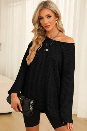 Black waffle knit oversized top with slit hem and off-the-shoulder neckline.