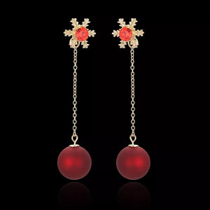 Deep red snowflake drop earrings with gold chain and red orb.