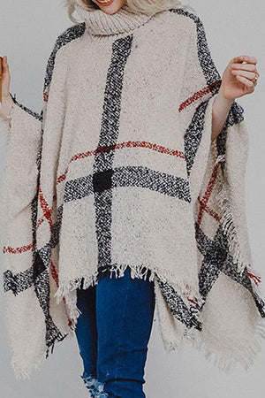 Beige plaid turtleneck cape with fringe detail and textured acrylic knit.