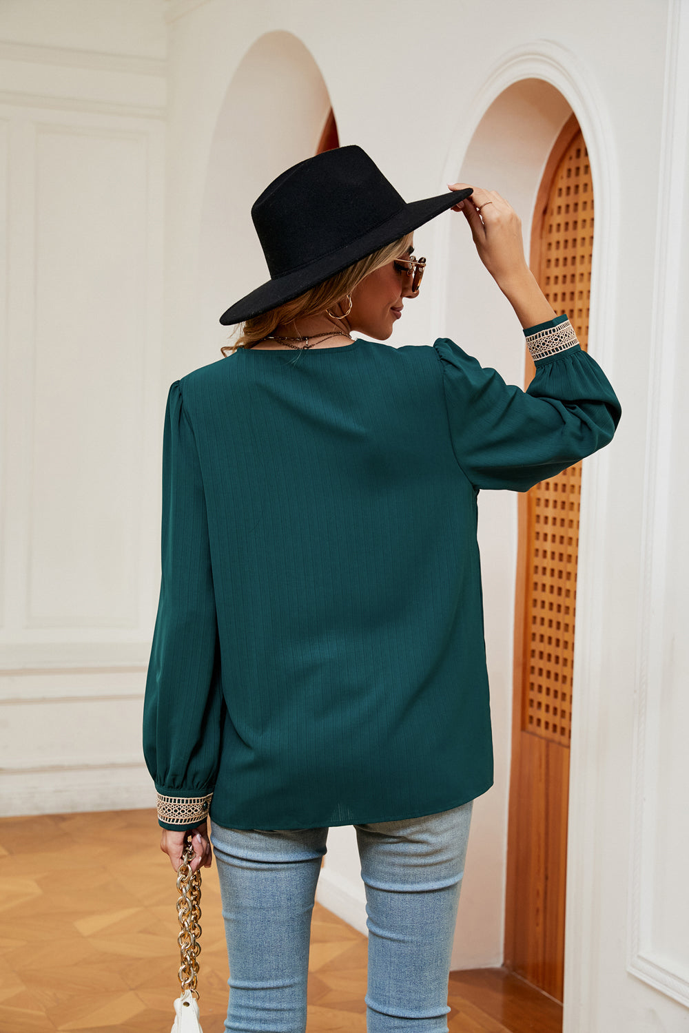 Green blouson top with embroidered trim on sleeves and subtle vertical ribbing.