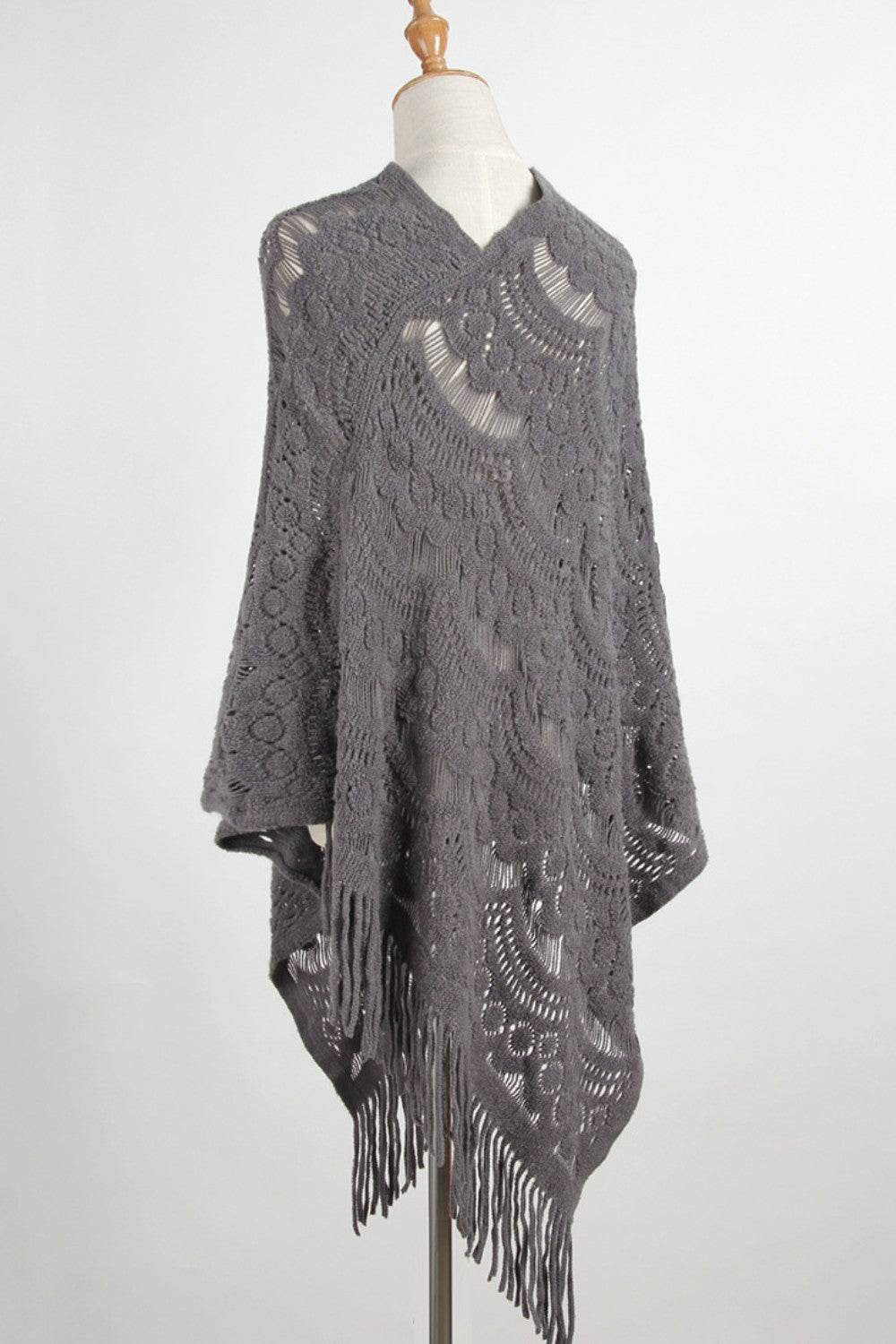 Dark gray crochet poncho with intricate openwork pattern and fringe detail.