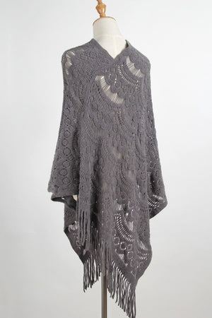 Dark gray crochet poncho with intricate openwork pattern and fringe detail.