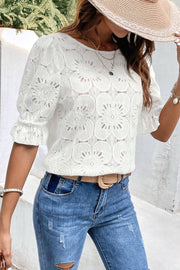 White eyelet blouse with puff sleeves and ruffled cuffs.