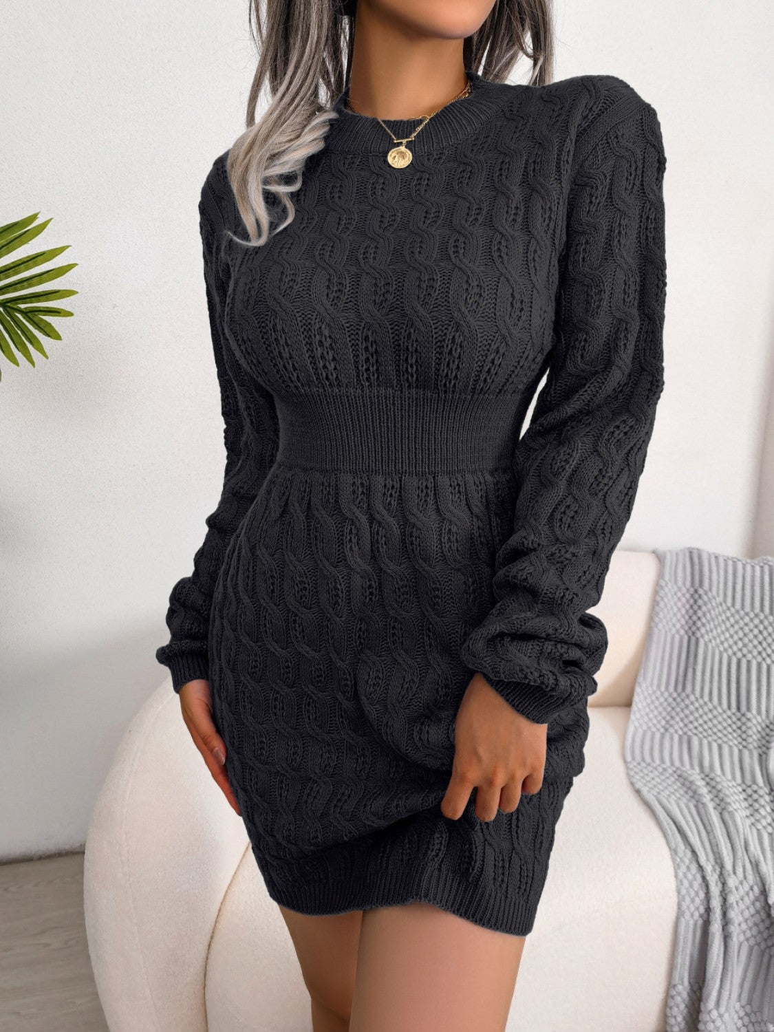 Black cable knit mini dress with long sleeves and a sculpted fit