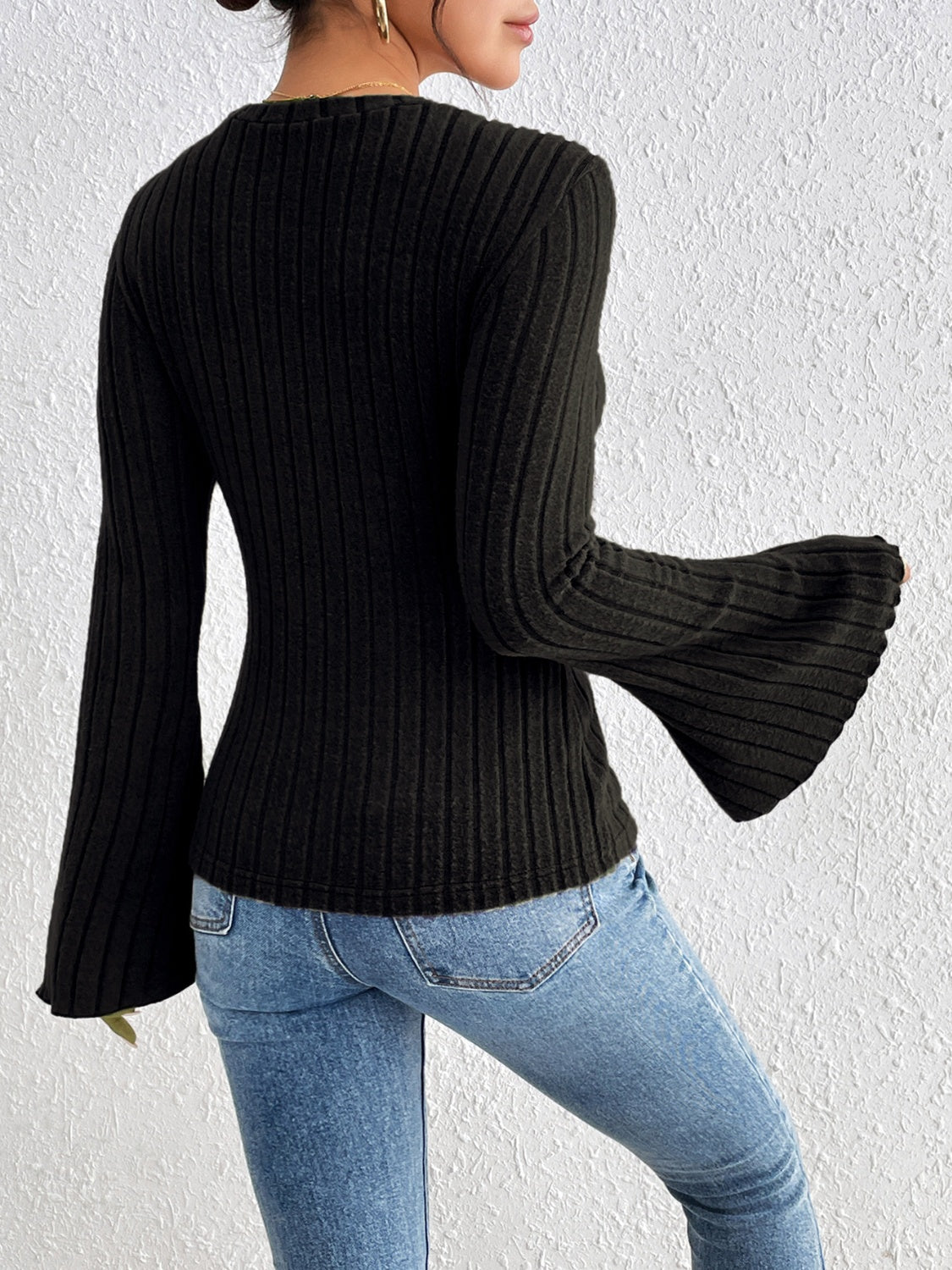 Black ribbed sweater with flared sleeves and a crew neck.