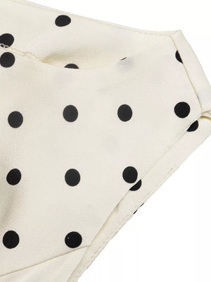 Cream peplum blouse with black polka dots and a folded neckline detail.