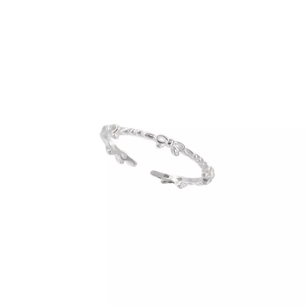 Delicate sterling silver ring with a repeating bow pattern.