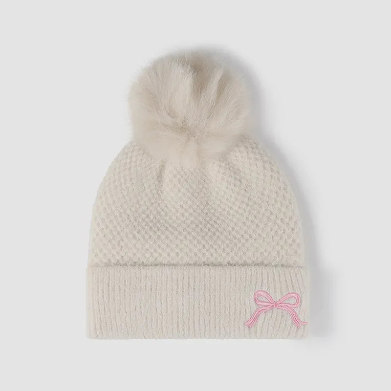 Beige knit beanie with pom-pom and pink bow detail