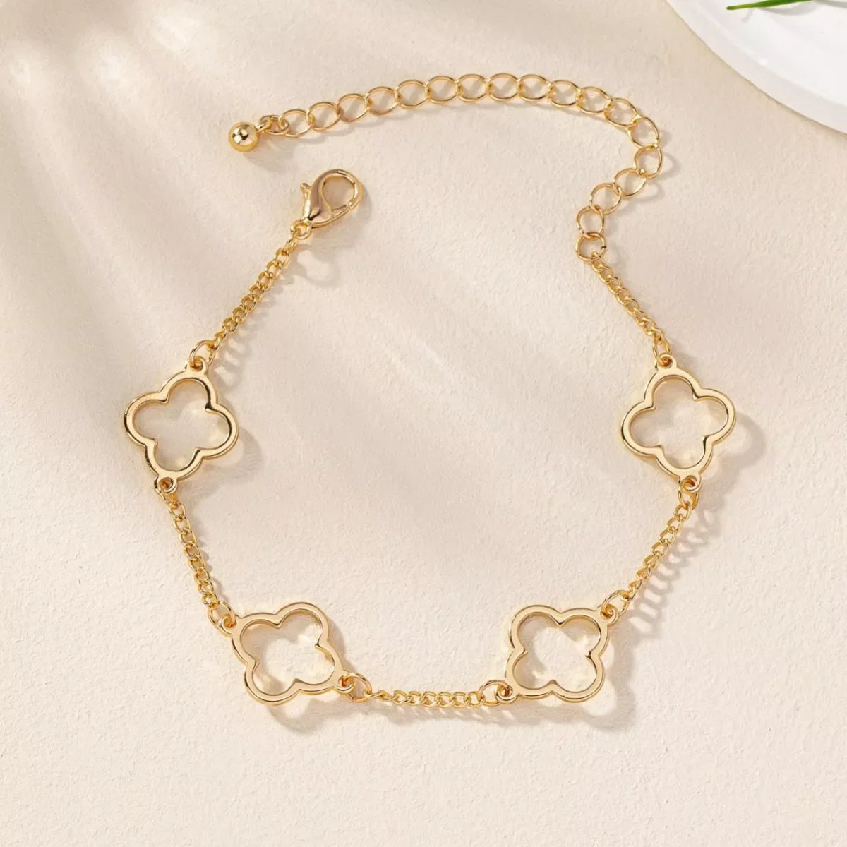 Gold four leaf clover charm bracelet with dainty chain and lobster clasp.