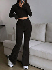 Black ribbed knit flare co-ord set with zip-neck crop top and high-waisted pants.