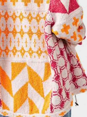 Geometric patchwork knit cardigan with orange, pink, and white patterns.