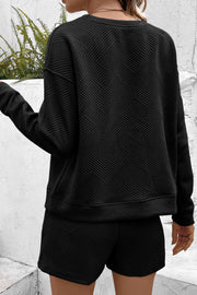 Black textured geometric lounge set with crew neck sweatshirt and shorts.