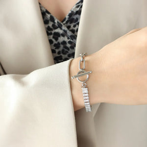Silver chain-link bracelet with toggle clasp and baguette zirconia charms.