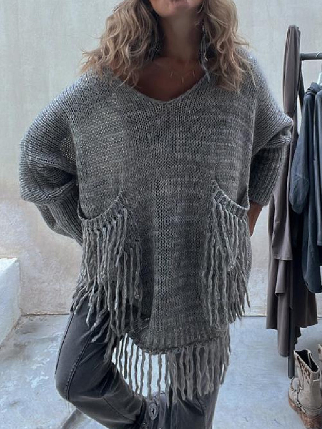 Dark gray knit poncho sweater with V-neck, fringed pockets, and a relaxed fit.