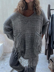 Dark gray knit poncho sweater with V-neck, fringed pockets, and a relaxed fit.